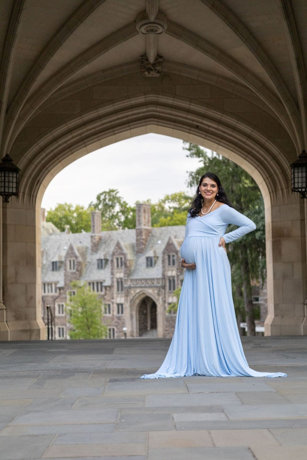 Maternity portrait in a light blue gown under Blair Arch, Princeton University