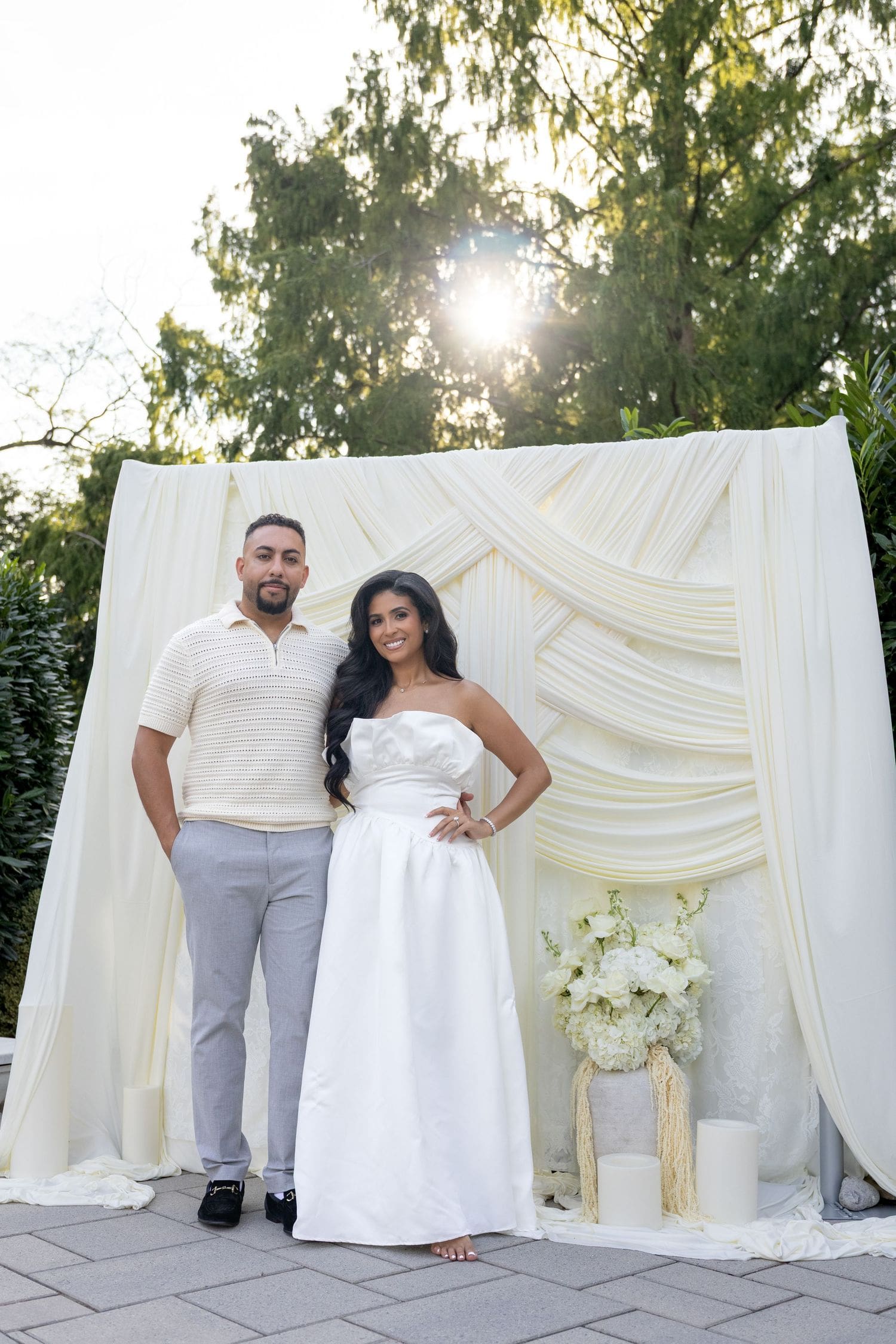 Bride-to-be and her fiancé in front of a draped white backdrop at her bridal shower
