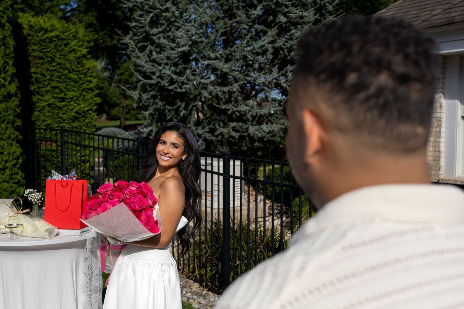 Bride-to-be holding red roses as her fiancé surprises her at the bridal shower