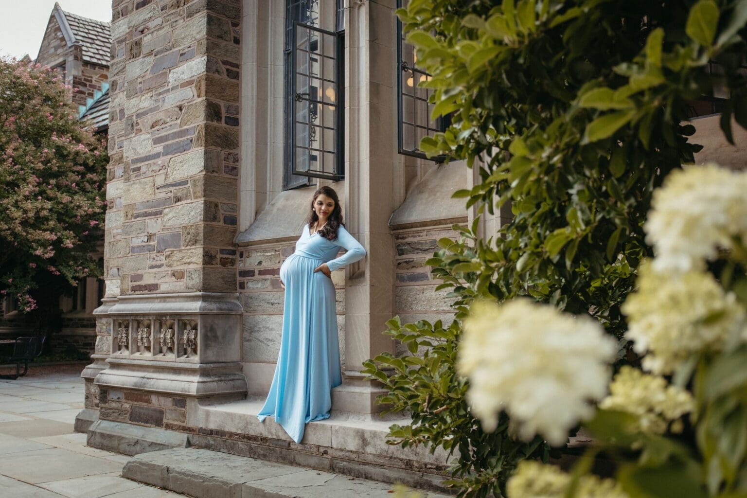 Maternity portrait in a blue gown beside East Pyne Hall, Princeton University