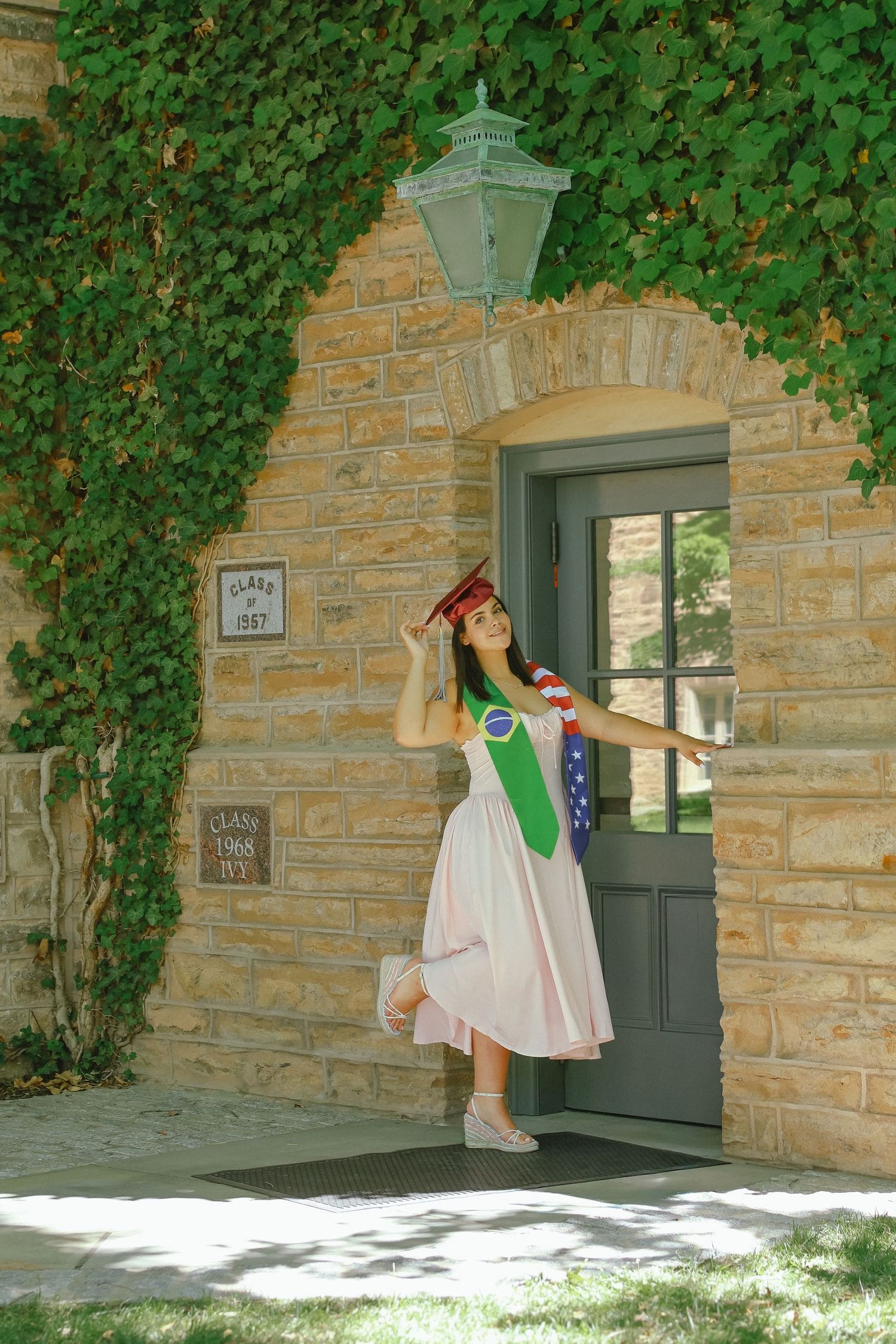 Graduate with a green stole at an ivy-covered doorway near Nassau Hall, Princeton