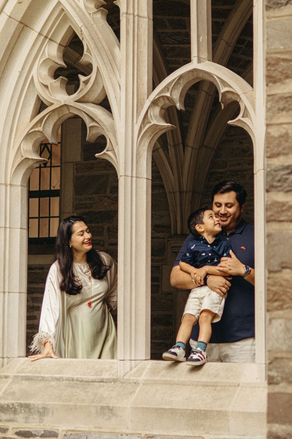 Family posing in a Gothic stone window at Rockefeller College, Princeton University